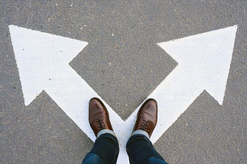 Person standing at crossroads with two arrows