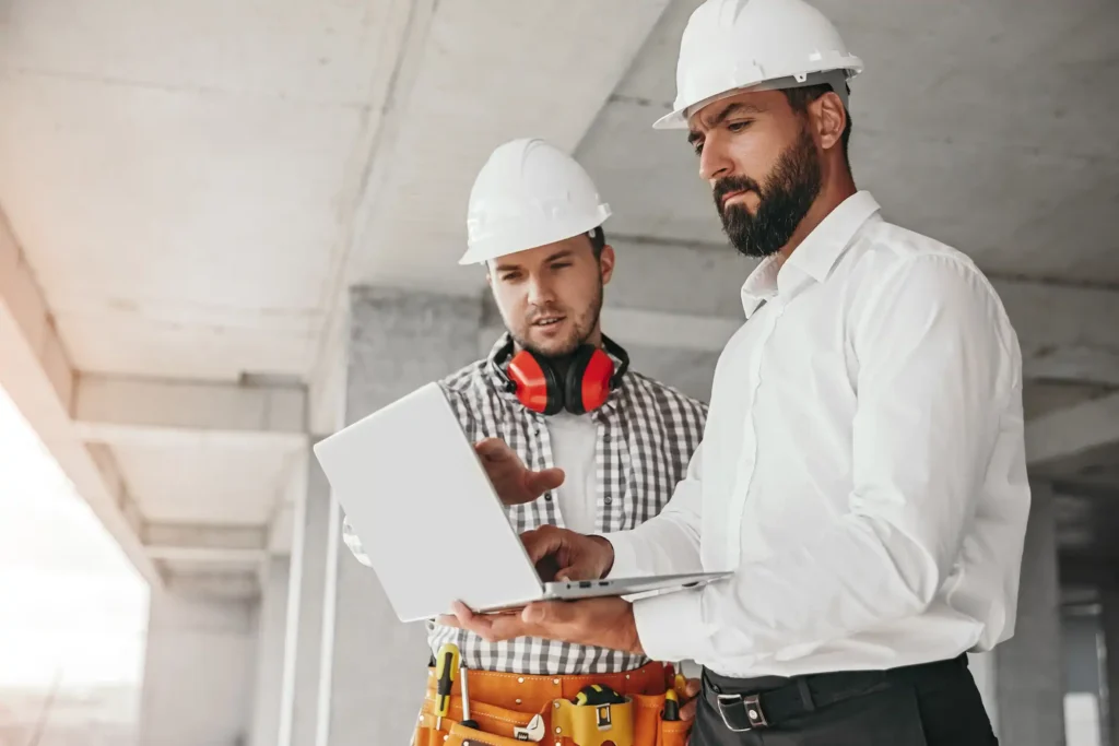 Male contractors using laptop on construction site