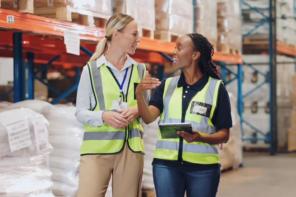 Women, tablet and partner in discussion at warehouse